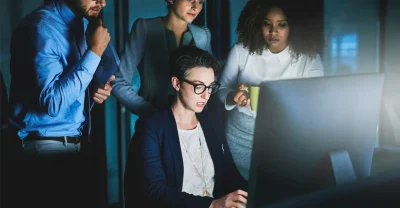 Equipe de profissionais de agência de criação de sites no RJ analisando projeto web em laptop